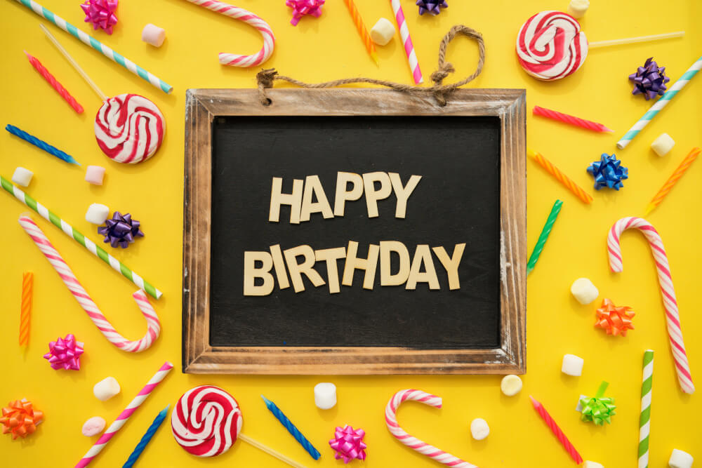 Bunte Happy-Birthday-Tafel mit Bonbons, Lutschern und Kerzen für Kindergeburtstag